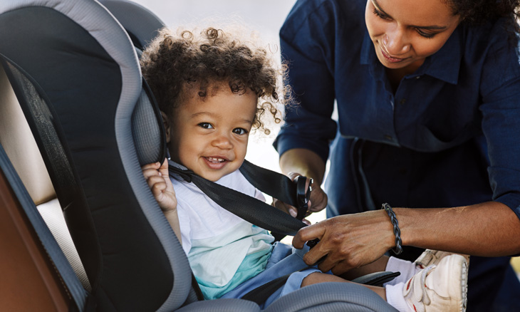 Mother fastening child in car seat