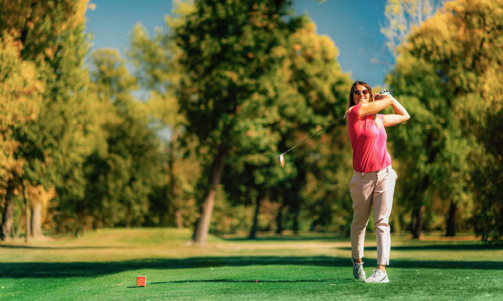 Woman swinging club on a golf course