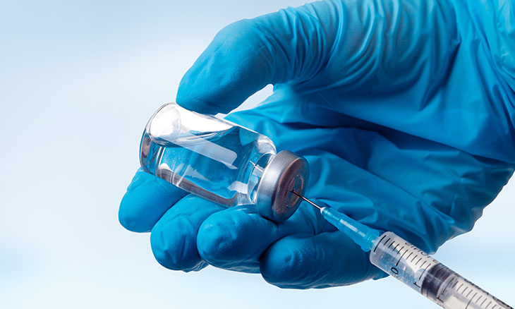 Hand filling a syringe with a dose of a vaccine