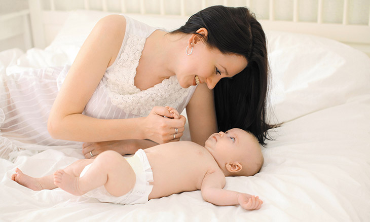 Mother bonding with infant on bed