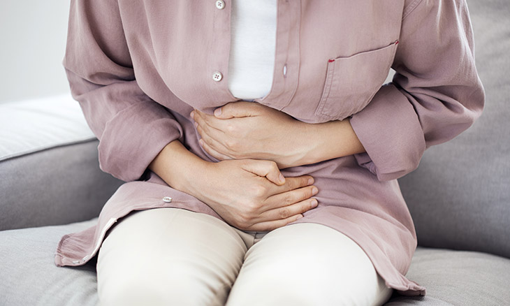 Woman holding her abdomen while having stomach pain