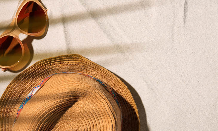 Sunglasses and large sun hat on the beach