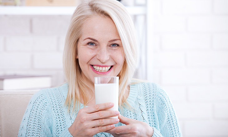 Woman holding a glass of milk to help prevent Osteoporosis