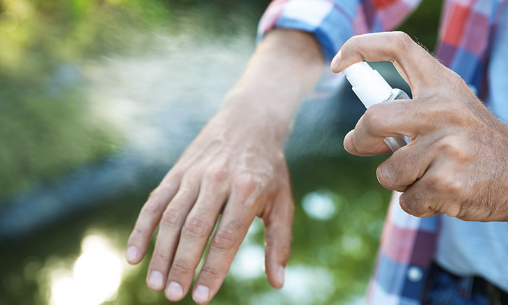 Woman spraying hand with bug spray