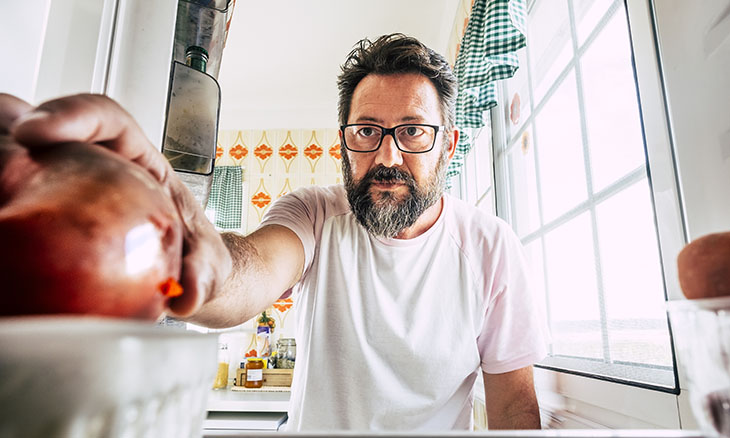 Lonely man reaches into refrigerator