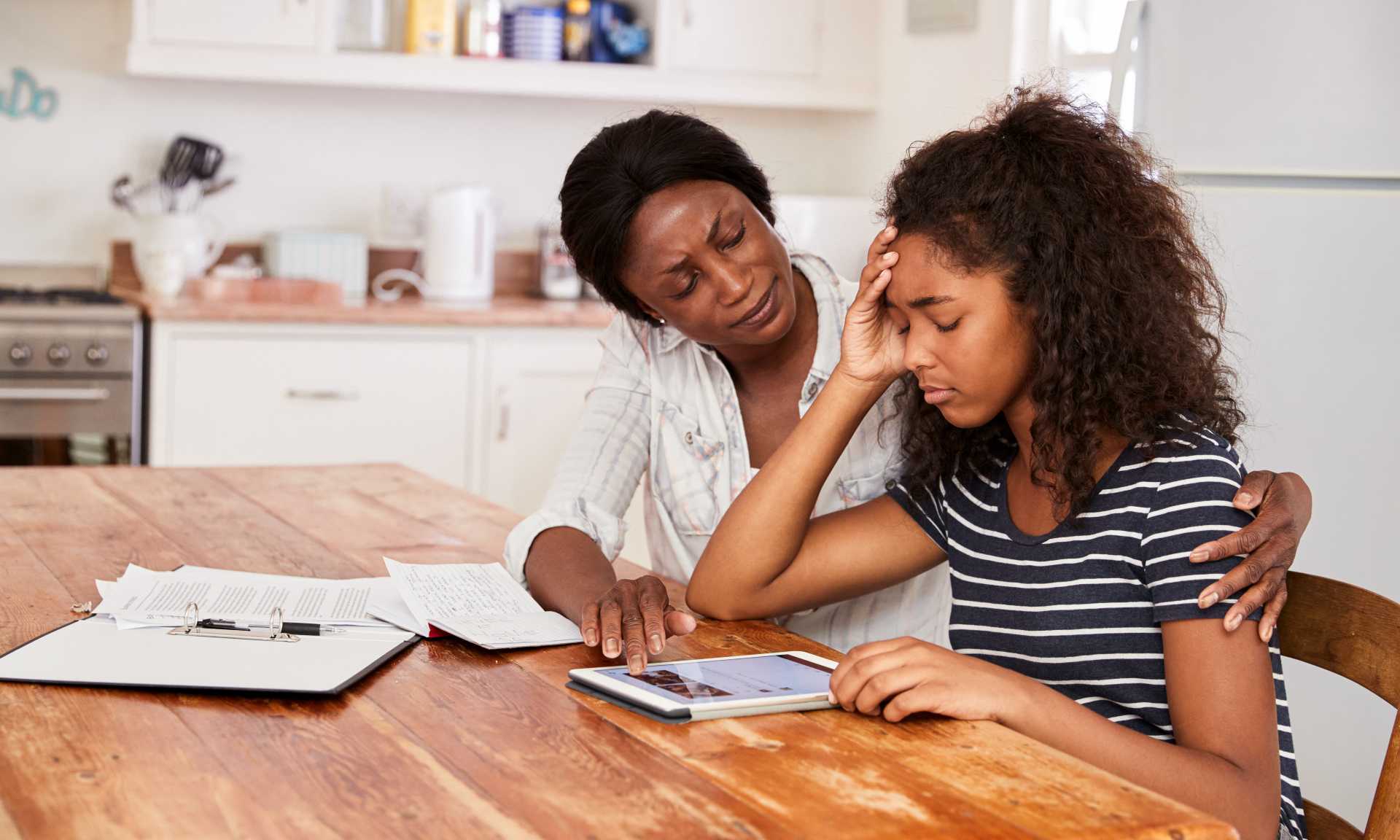 Mom helping stressed teen with schoolwork.