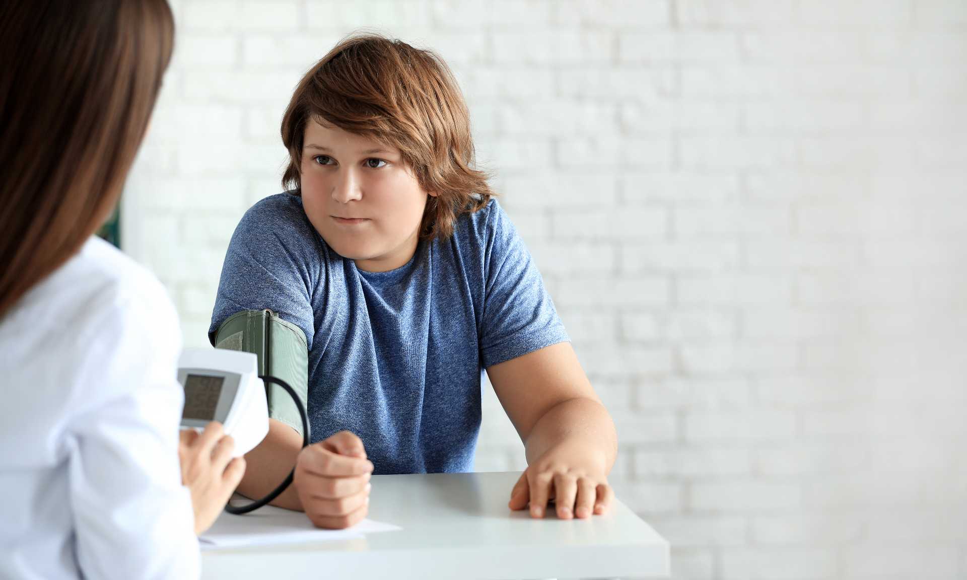 Teenage boy has his blood pressure taken by doctor.