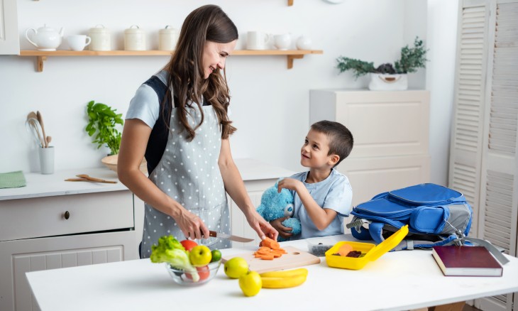 A mother cuts up veggies to put in her son's school lunch