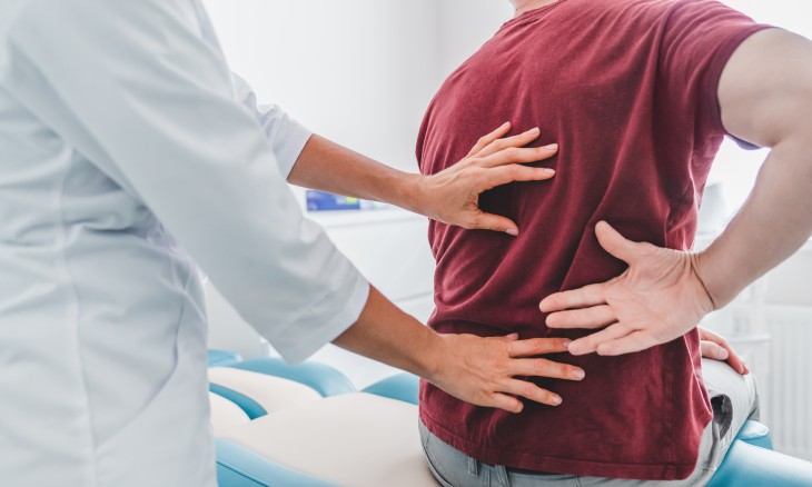 Doctor examining a patient's back during an OMT appointment
