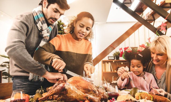 A family carves a Thanksgiving turkey.