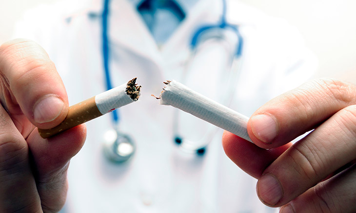 A doctor breaks a cigarette in half.