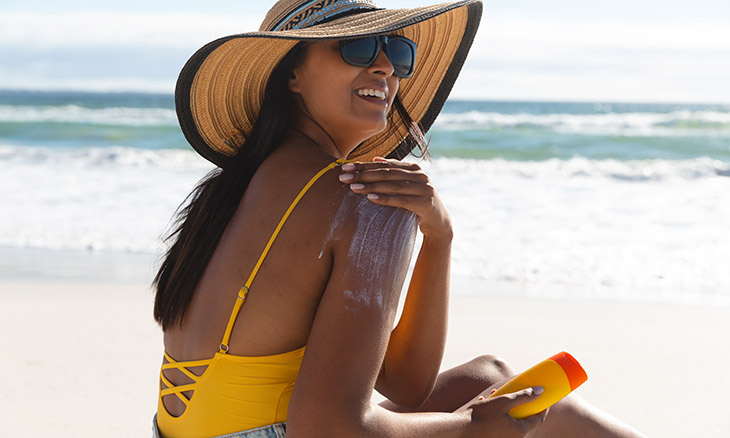 A woman applies sunscreen while at the beach