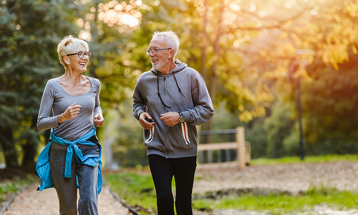 A couple jogs together in a park.