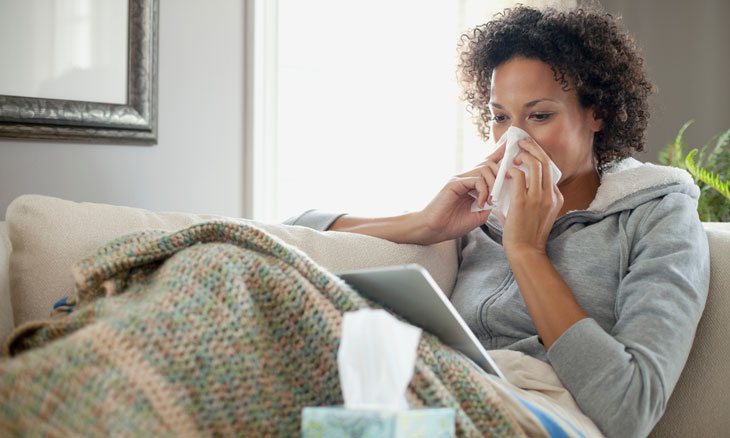 Women blowing her nose as she searches on a tablet