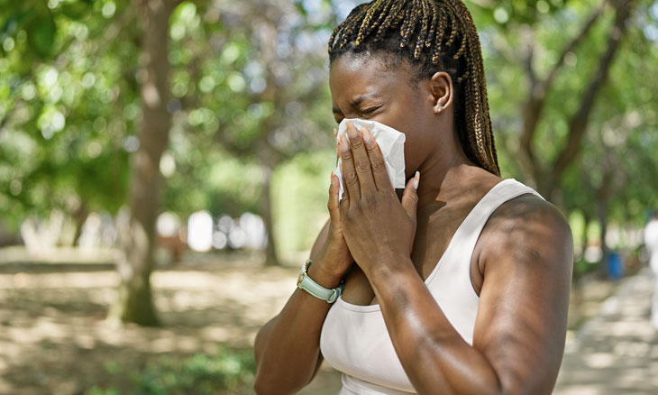 Woman sneezing into a tissue