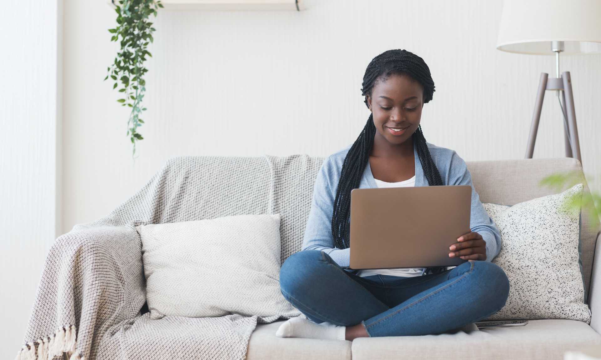 Young woman sitting on her couch with laptop