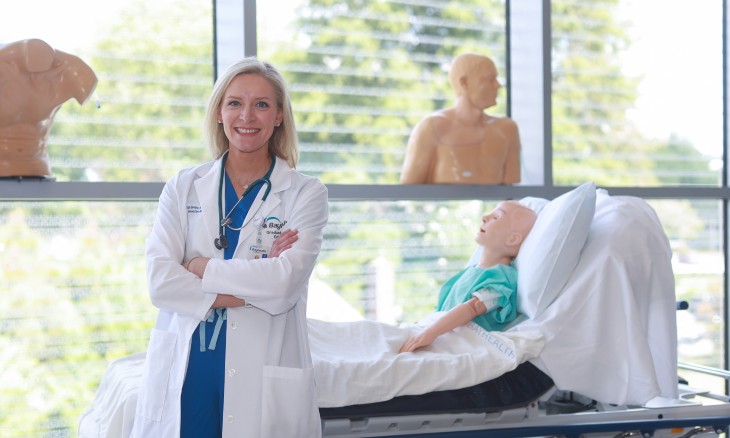 Bayhealth GME Simulation Lab Program Manager Sarah Beebe stands in the new PCOM Simulation Center at Bayhealth with some of the simulation manikins. 