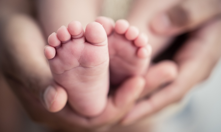 A baby's feet are cradled in mom's hands.