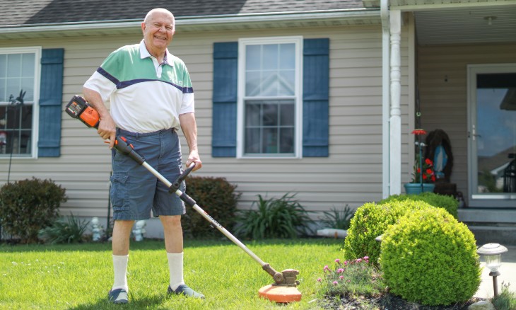 Man holding a trimmer about to do yard work outside his home