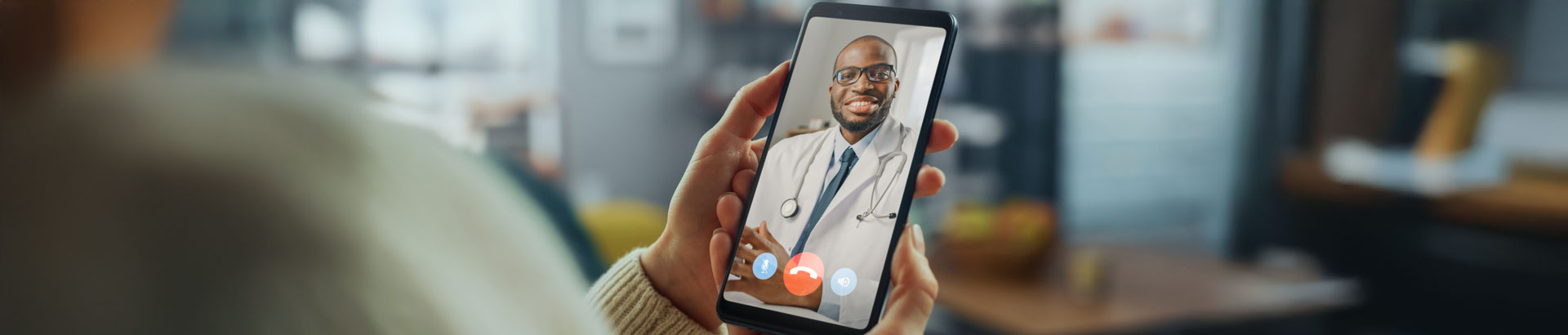 Looking over the shoulder of a patient speaking to a doctor on their smart phone.