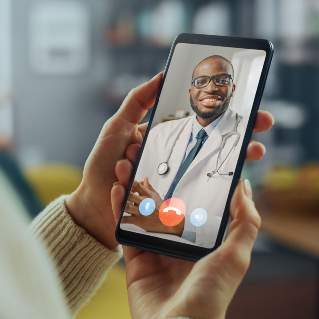 Looking over the shoulder of a patient speaking to a doctor on their smart phone.