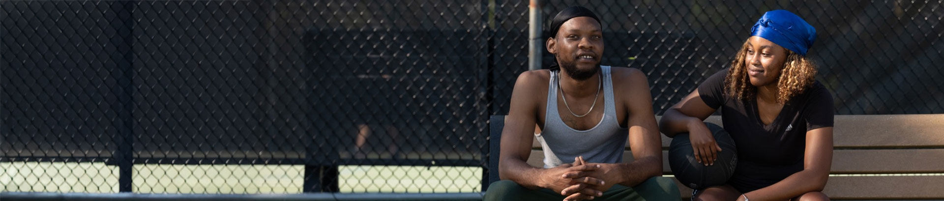 Couple sitting on a bench at basketball courts