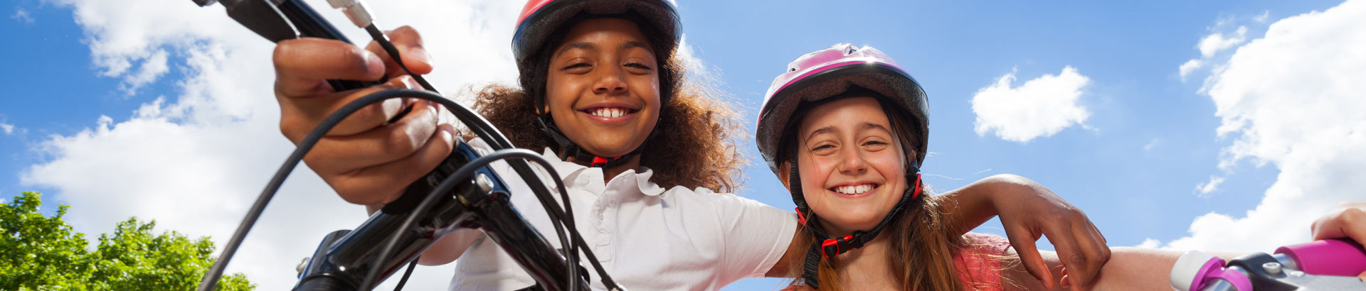 Two girls on bikes smiling