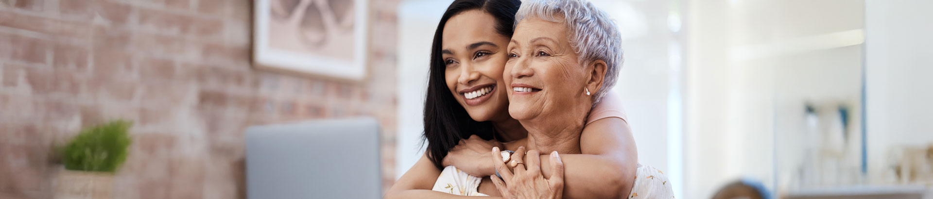 Daughter hugs mom as they read from laptop.