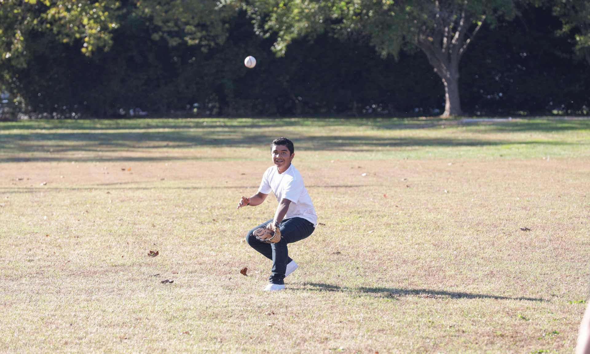 Preteen boy catching a baseball in his glove at the park