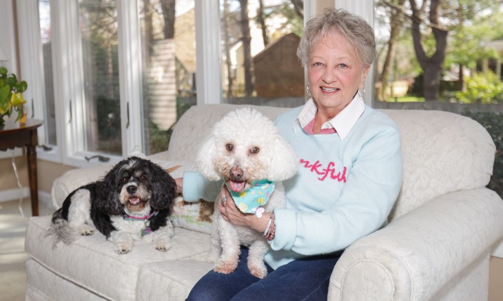 Patient sitting on the couch with her two dogs.