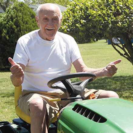TAVR patient George DeCaro riding on his lawn mower.